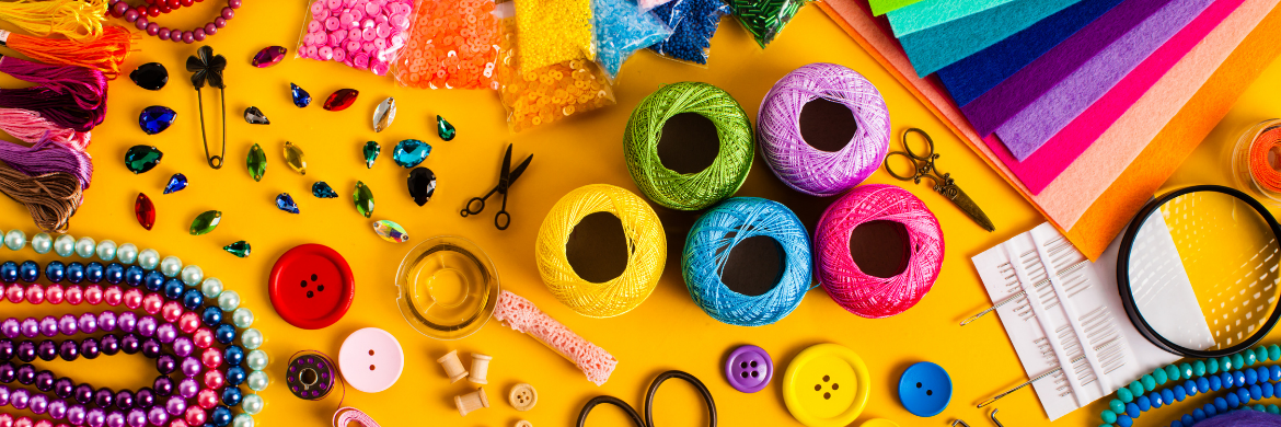 Colorful arts and crafts supplies spread out on a yellow table