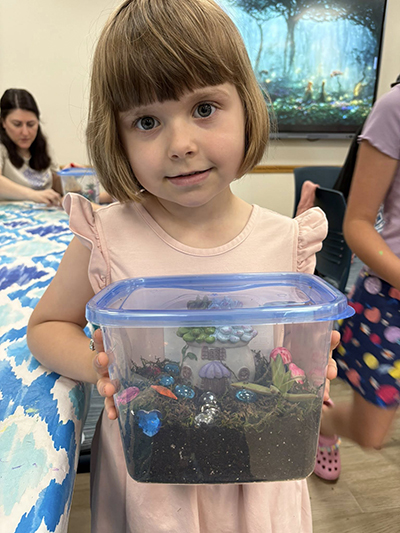 Young girl in a pink dress holding a fairy terrarium