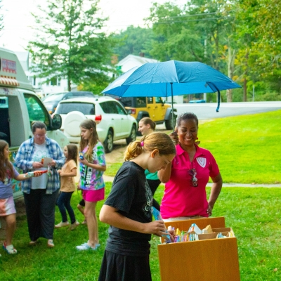 Person holding umbrella and child making ice cream