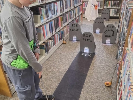 boy playing headstones hole mini-golf course