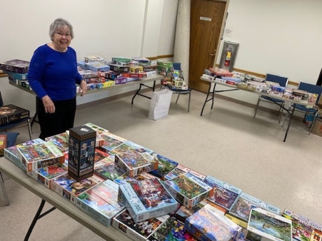 woman standing in front tables stacked with puzzles. 