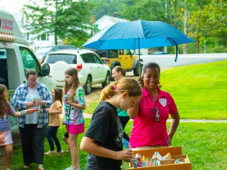 Person holding umbrella and child making ice cream