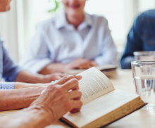 Person holding an open book while sitting in a group
