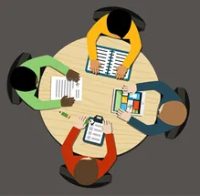 Four people sit around a circular table, viewed from above. They are engaged with documents, tablets, and a clipboard, symbolizing a collaborative meeting.