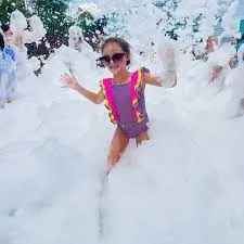 A lively scene of children enjoying themselves as they play in a thick layer of foam, creating a fun and playful atmosphere.