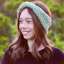 A young girl with a pale green yarn headband around her head.