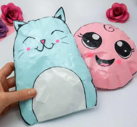 Handmade stuffed paper squishies in the shape of a blue cat and a pink smiley face.