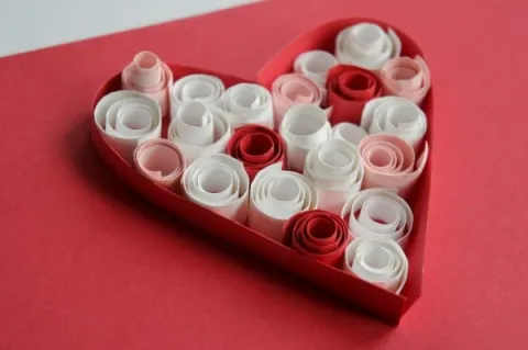 A red, white, and pink heart made by quilling paper.