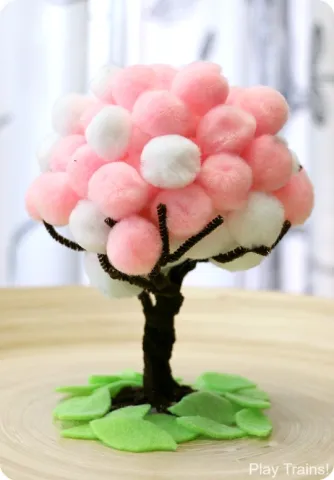 A pink and white cherry tree made out of pompoms and pipe cleaners.