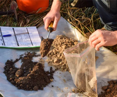 A person with a sample of dirt using a soil test kit