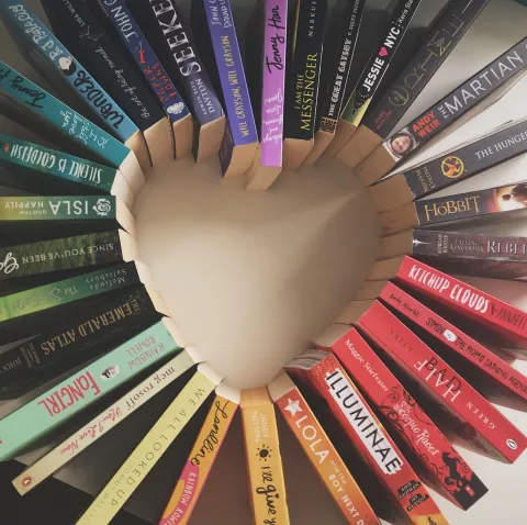 Multi colored books placed spine up in the shape of a heart