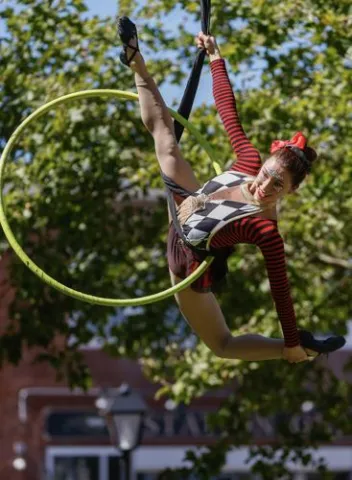An aerialist on silks with a hula hoop.