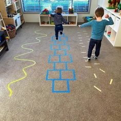 Children follow the lines of a duct tape obstacle course along a floor.