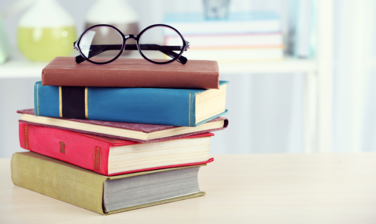 Stack of books with reading glasses on top